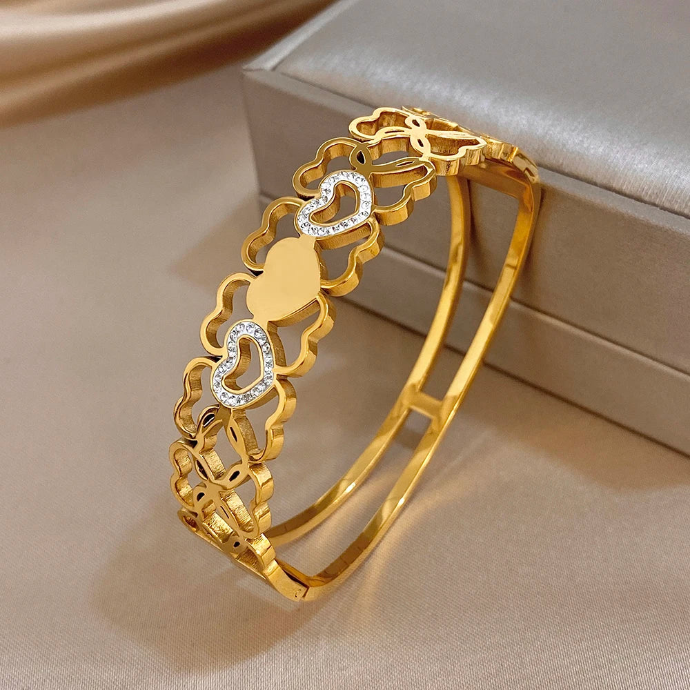 Gold cuff bangle angled view with hollow heart links and clear rhinestone details