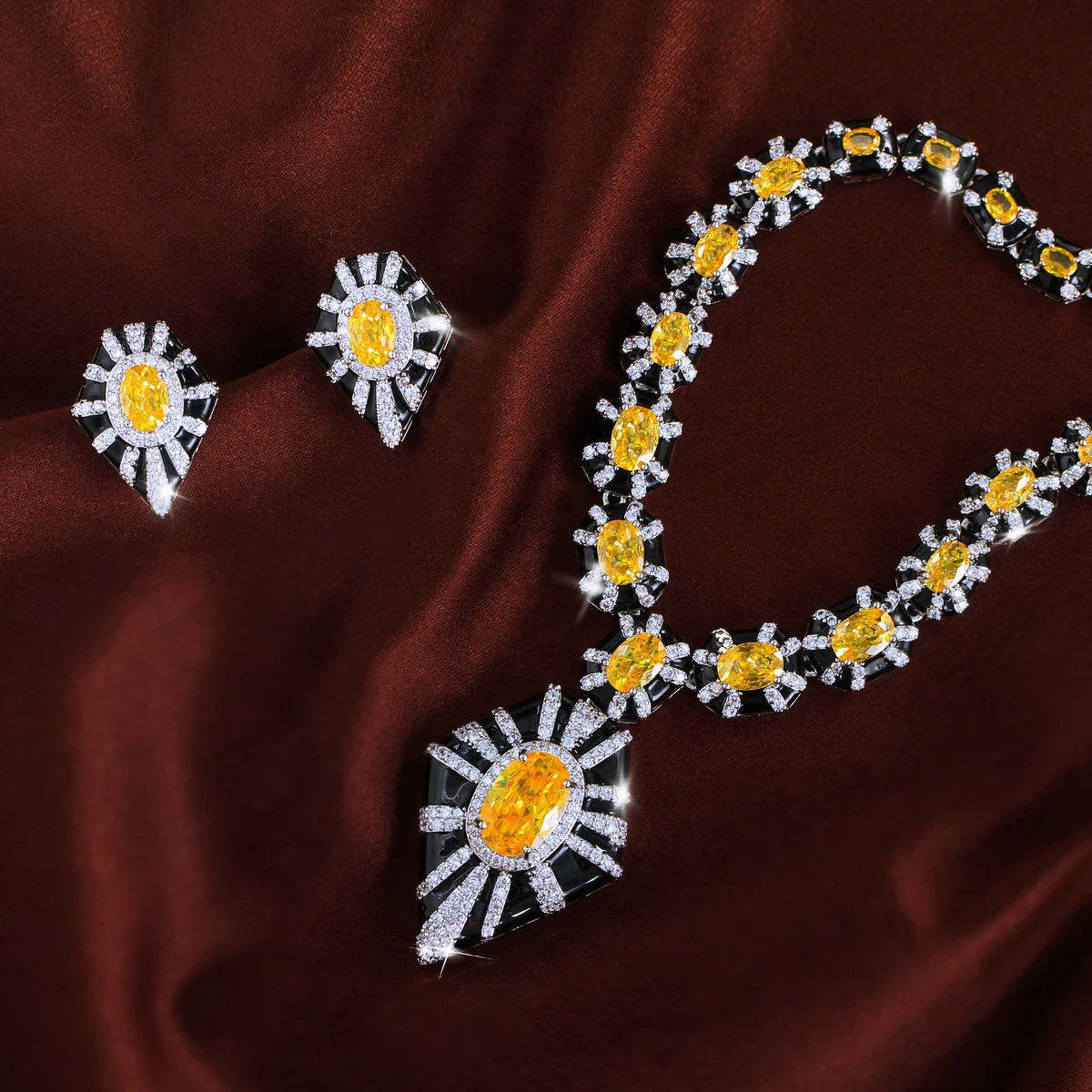 Necklace and matching earrings with yellow stones, clear accents, black enamel, and a sunburst pendant.