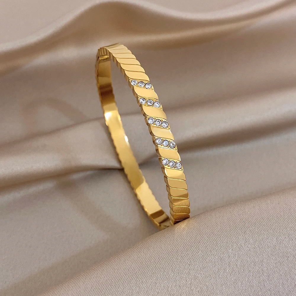 Gold tone ridged bangle with clear rhinestone row along the top edge