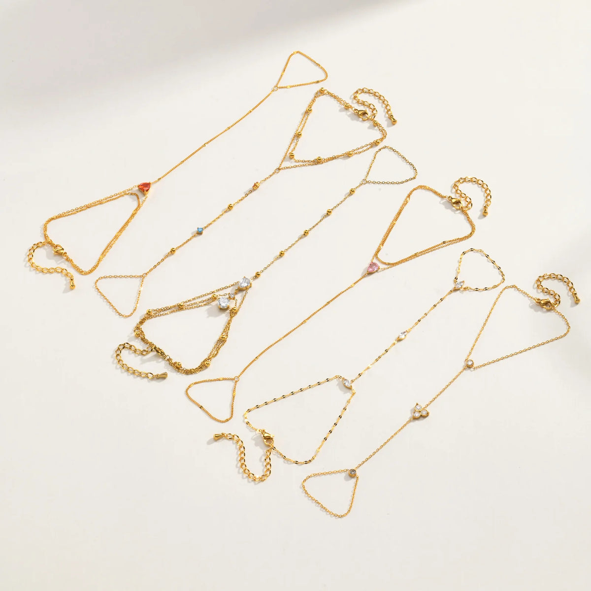 Gold-tone heart and CZ hand chain bracelets set with dangling clasps