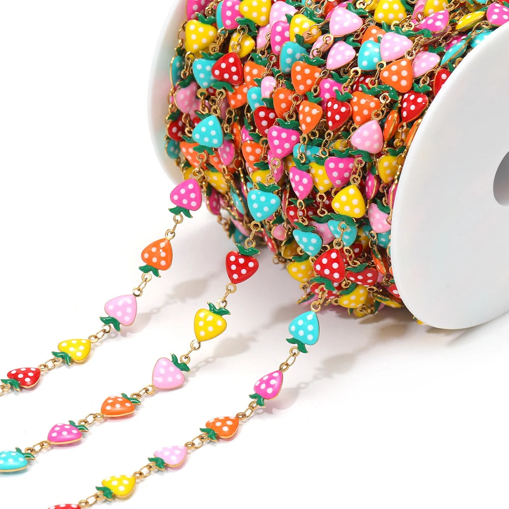 Multicolor enamel strawberry charm chain with gold-tone links on a spool for DIY jewelry