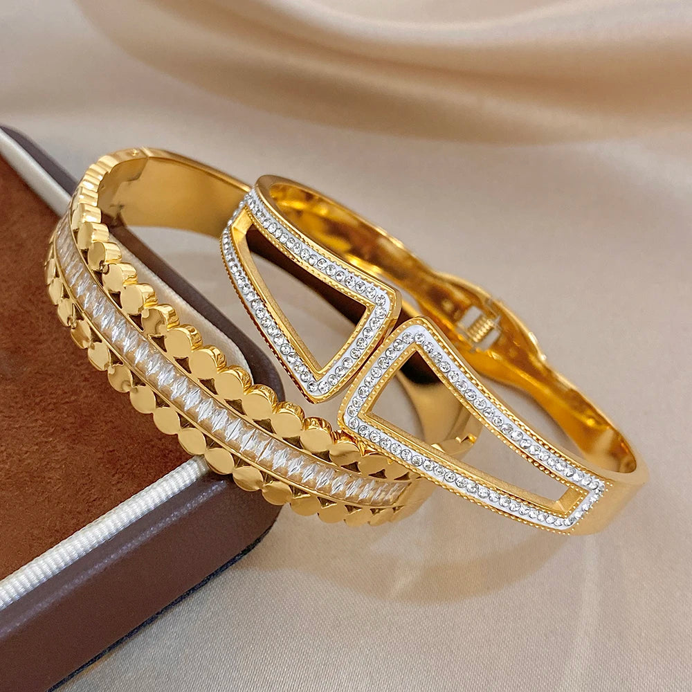 Gold-tone wide cuff bangle with geometric window design and clear rhinestone edging