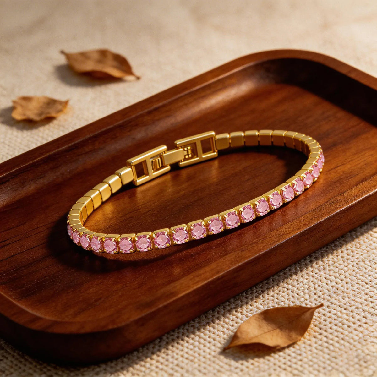 Gold-tone tennis bracelet with pink cubic zirconia stones and hinged clasp