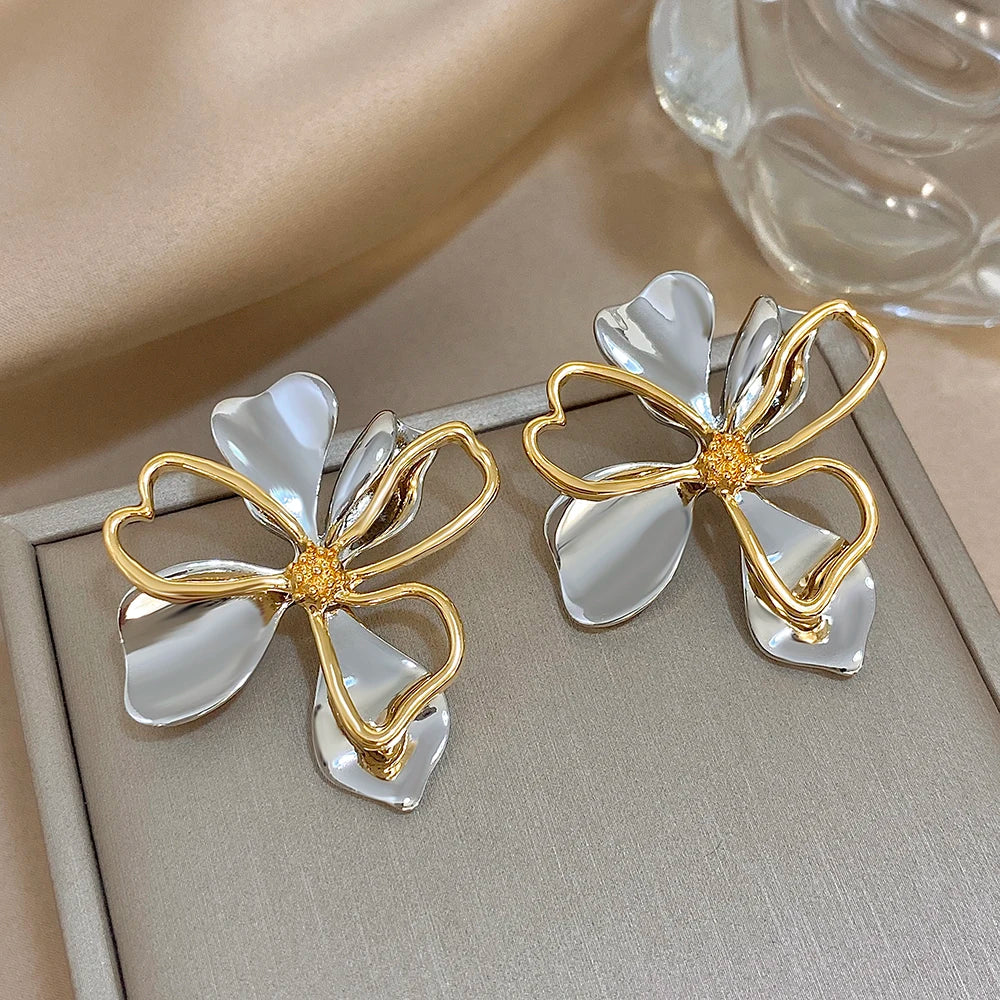 Silver-tone flower earrings with gold outline petals and textured centers