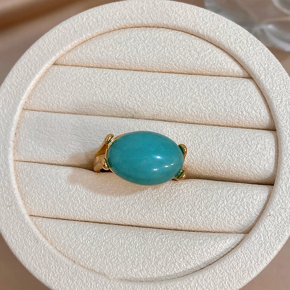 Gold-tone oval turquoise gemstone ring on white jewelry cushion