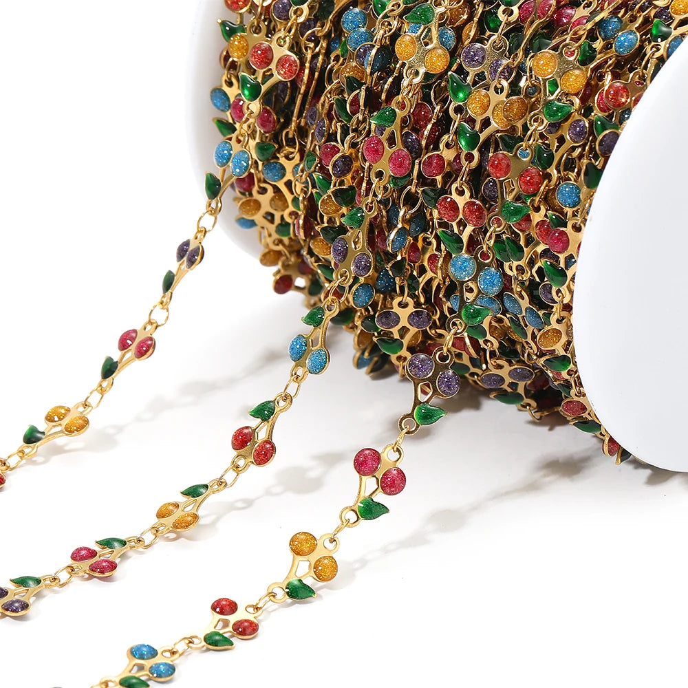 Close-up multicolor cherry charm chain with gold links and blue, green, and pink enamel