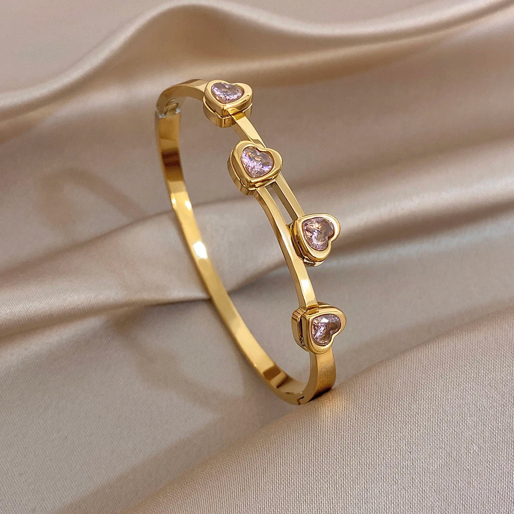 Gold-plated cuff bangle with small heart-shaped zircon stones in a line