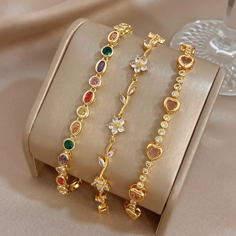 Gold-tone bracelet set with rainbow oval stones, heart links, and flower charm accents
