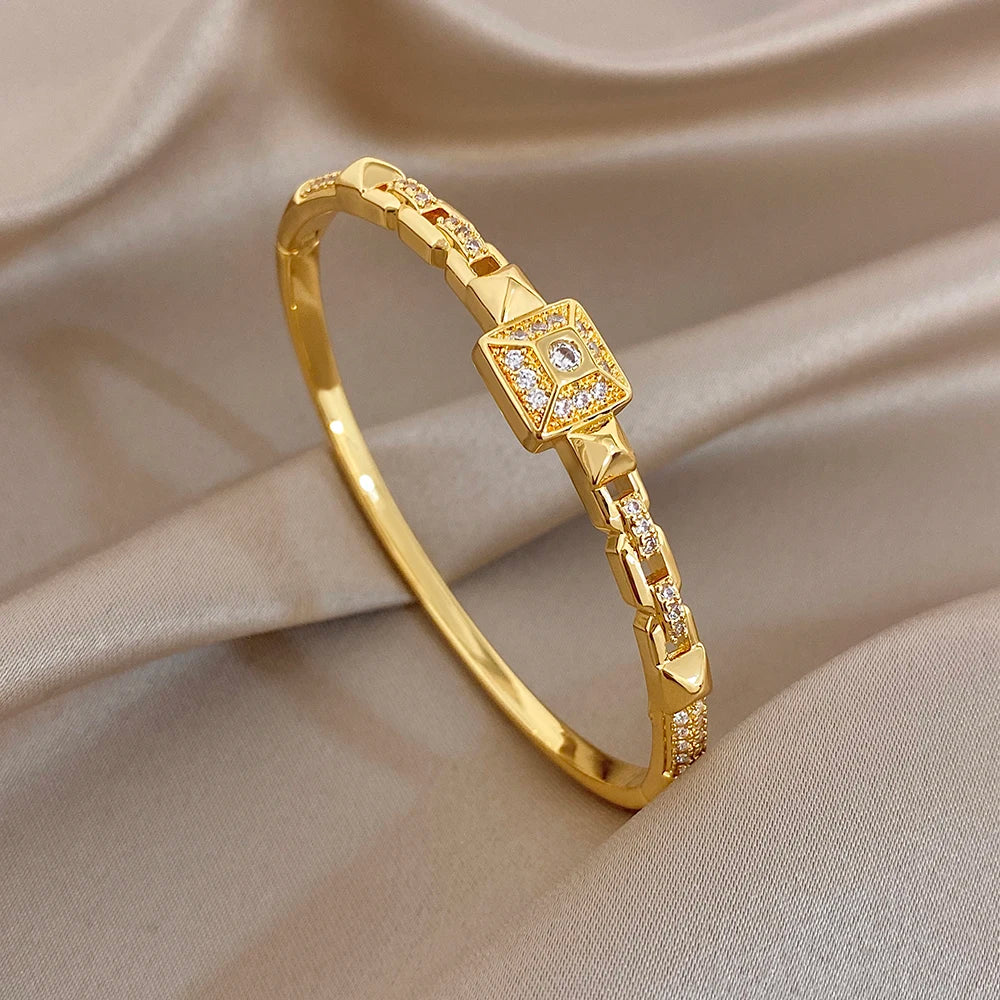 Gold-plated cuff bangle with a large square zirconia centerpiece and small link stones