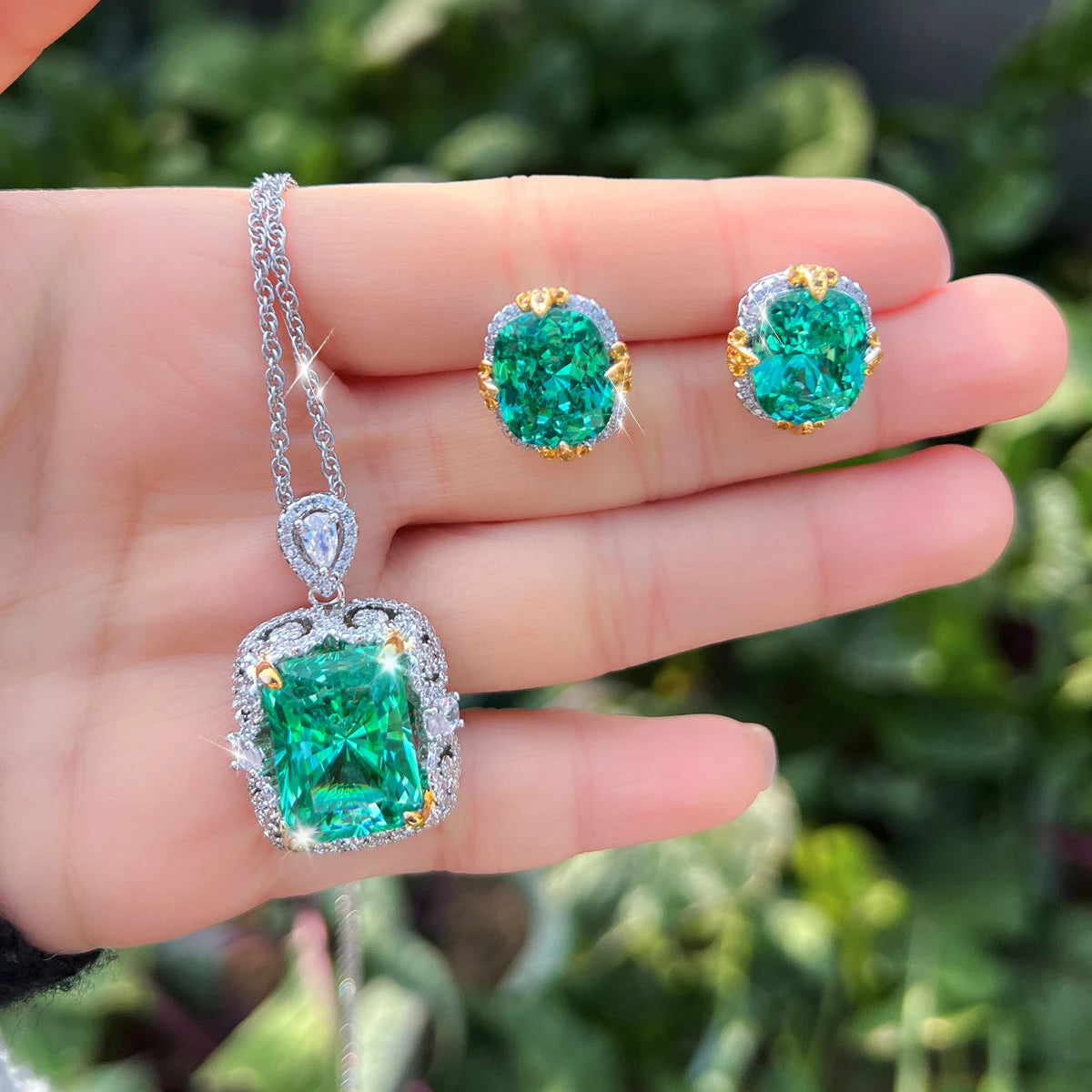 Green crystal necklace and matching oval earrings displayed in a hand