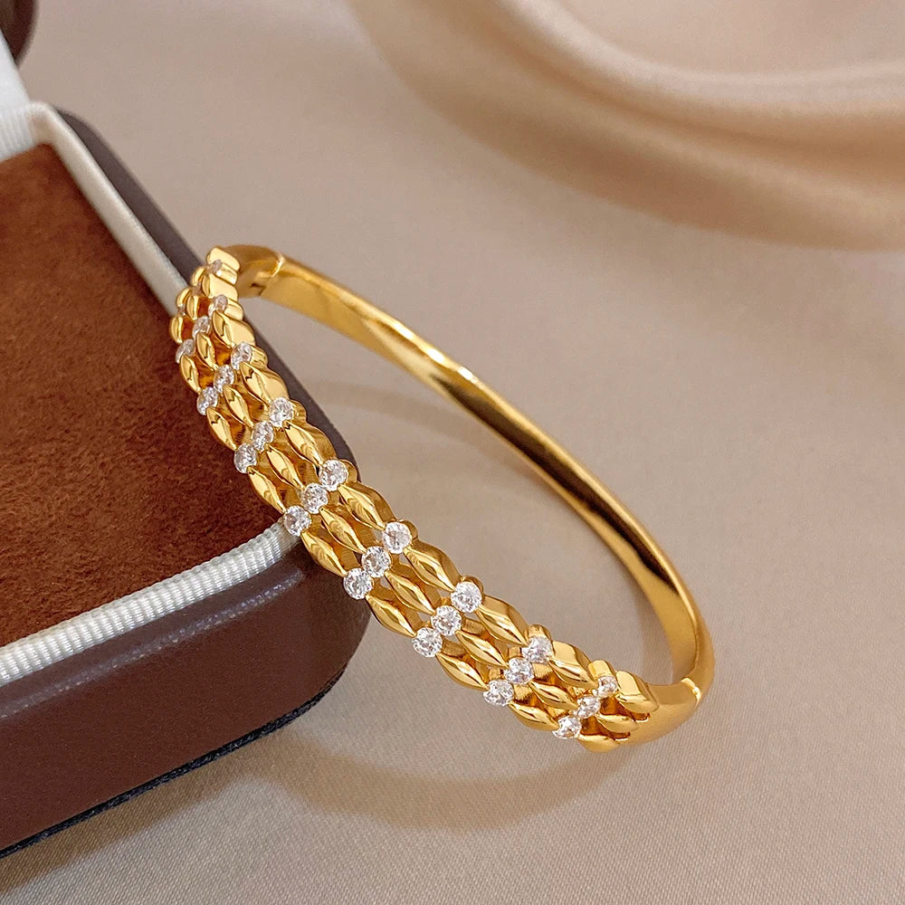 Gold cuff bangle with woven-texture links and alternating round stone clusters