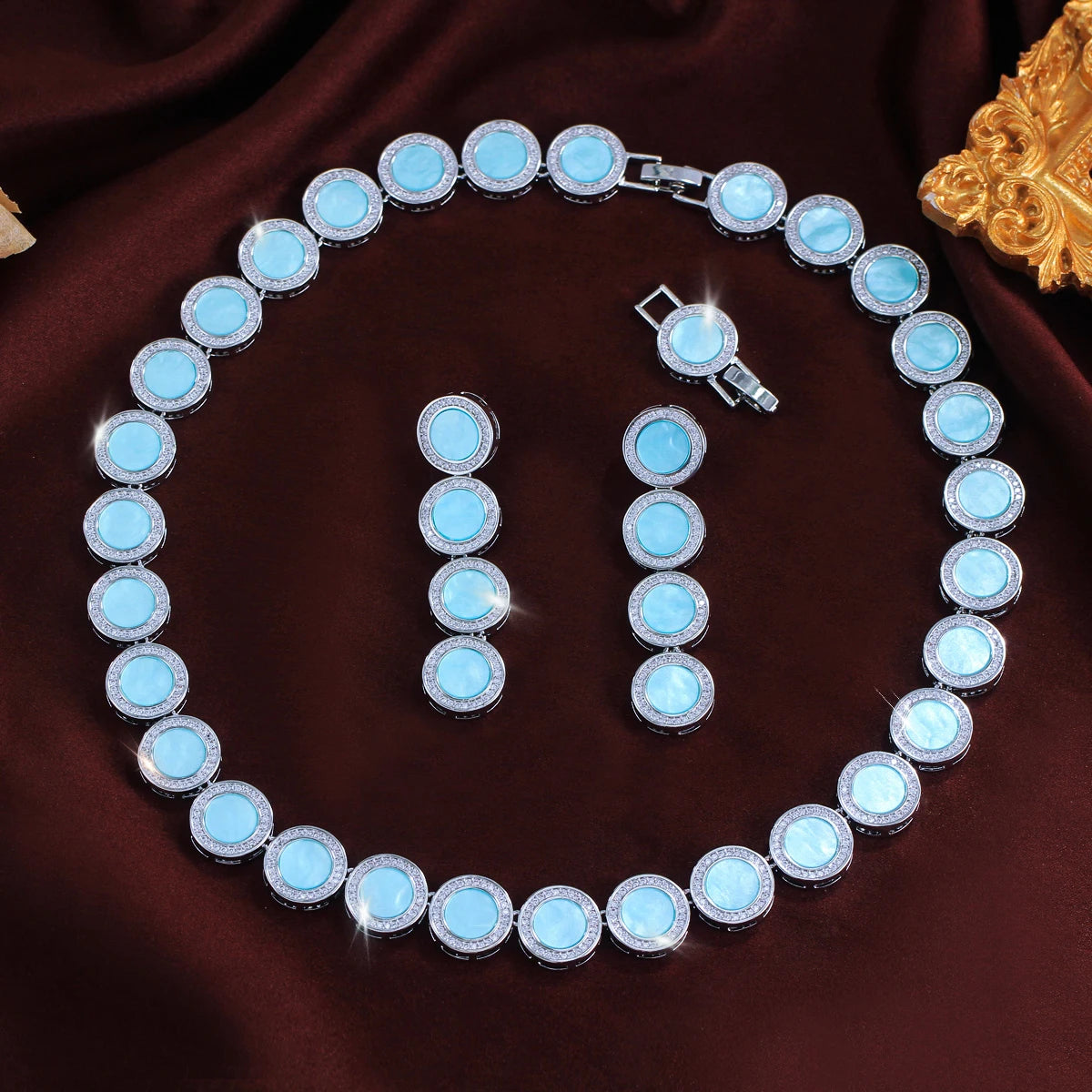 Light blue round halo necklace with matching drop earrings displayed flat