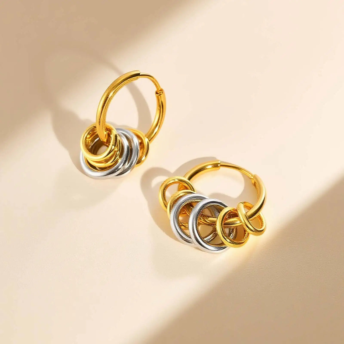 Pair of gold-tone hoop earrings with sliding gold and silver rings.