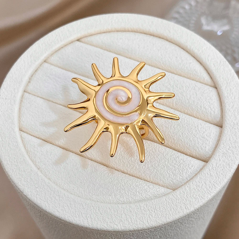Gold-plated sunburst ring with pale lavender spiral enamel on white ring cushion