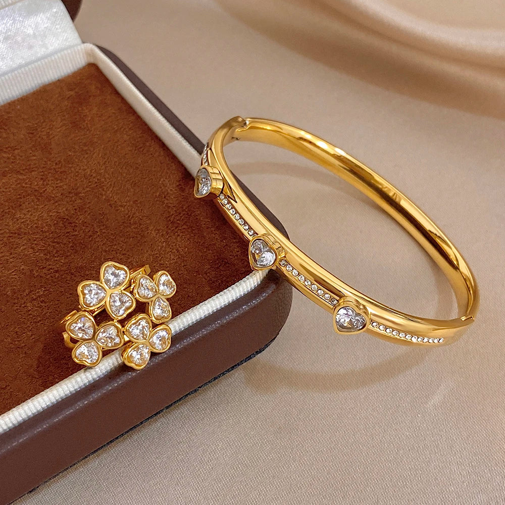 Gold-tone heart-stone bangle bracelet paired with flower cluster ring and clear gems