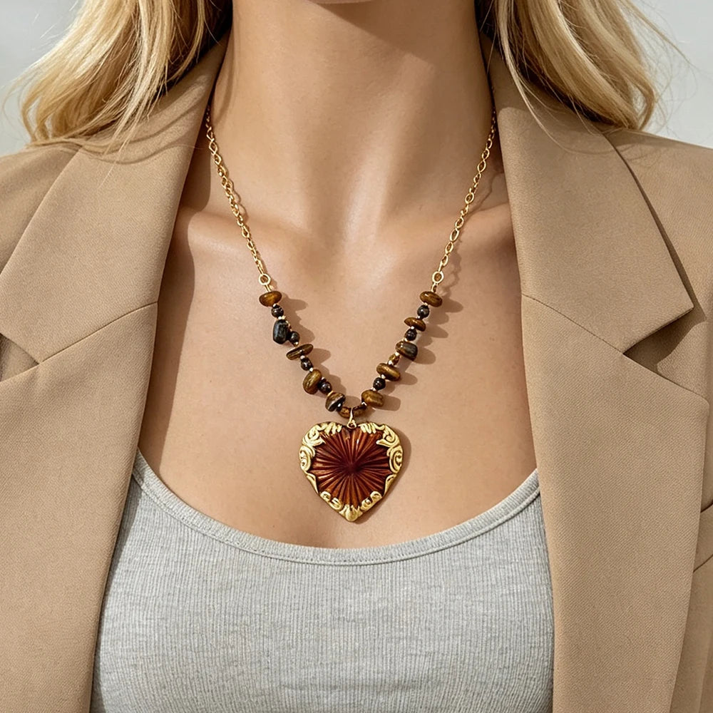 Gold heart pendant necklace with red sunburst heart charm on a neckline