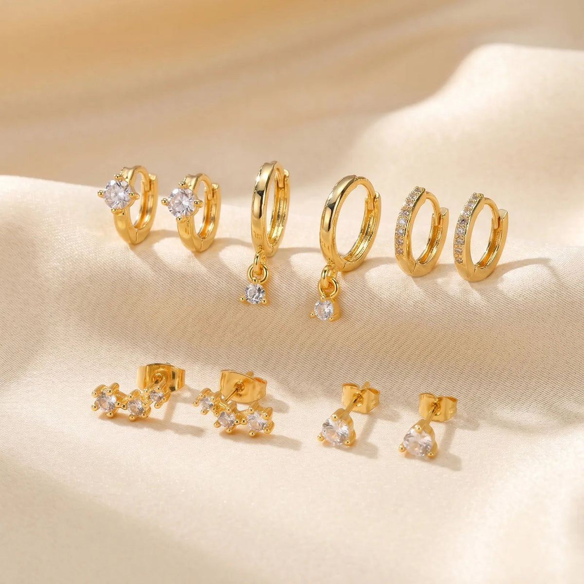 Gold-plated CZ hoop and stud earring set, assorted huggie hoops and drops on display