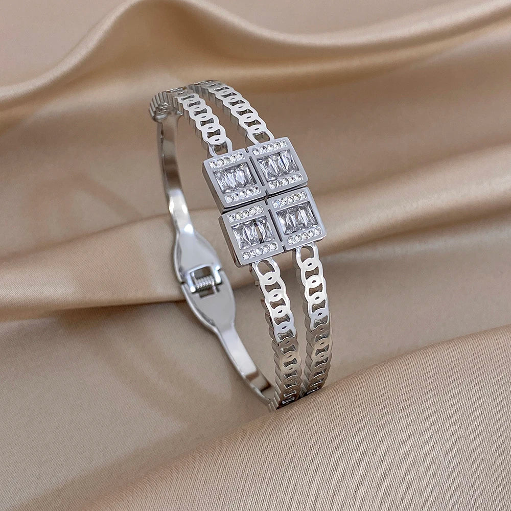Silver-toned zircon cuff bracelet with square grid centerpiece and dangling links detail