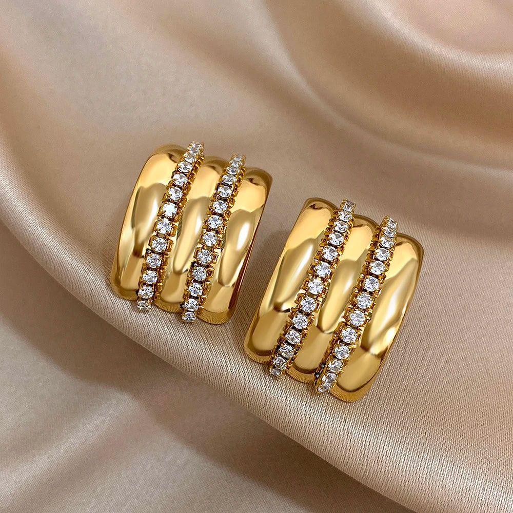 Gold-tone stud earrings with twin clear rhinestone rows across polished ridged bands