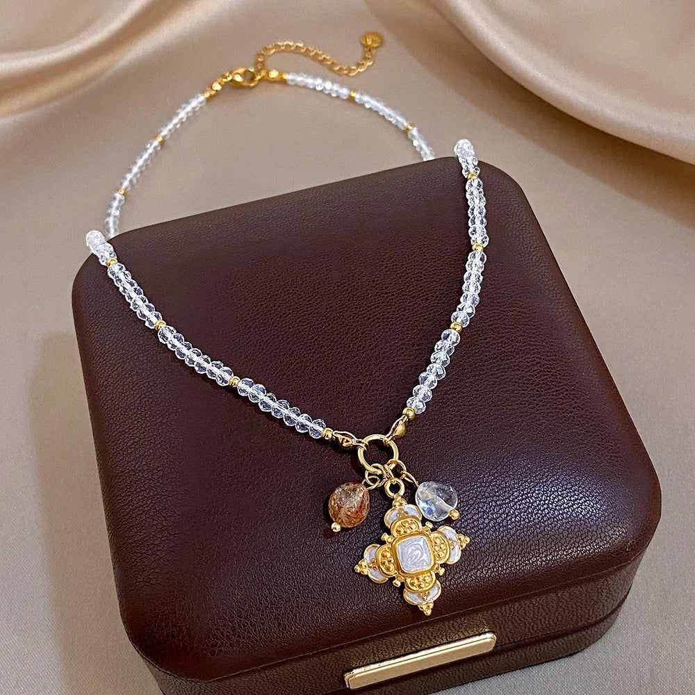 Gold-tone cross pendant necklace with clear crystal drops on a silver beaded chain