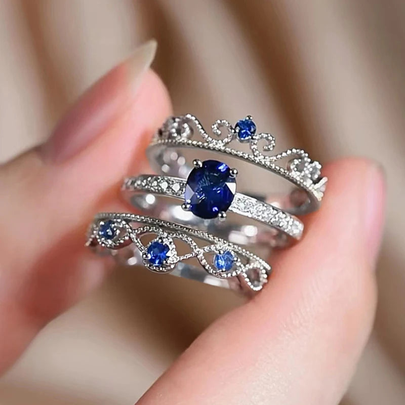 Three blue CZ rings with crown-like heart filigree and sparkling silver bands