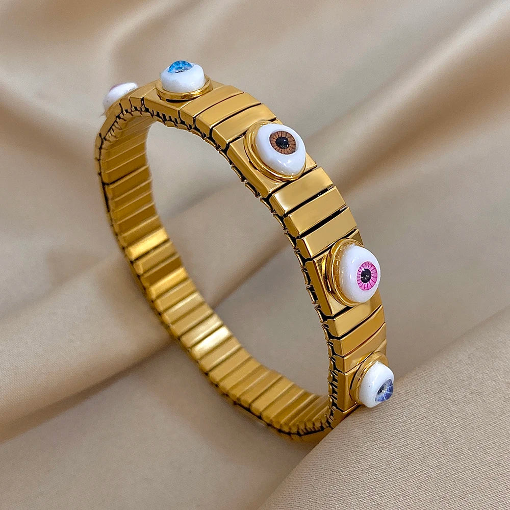 Gold-tone elastic bracelet with glossy oval evil eye insets on metallic link segments