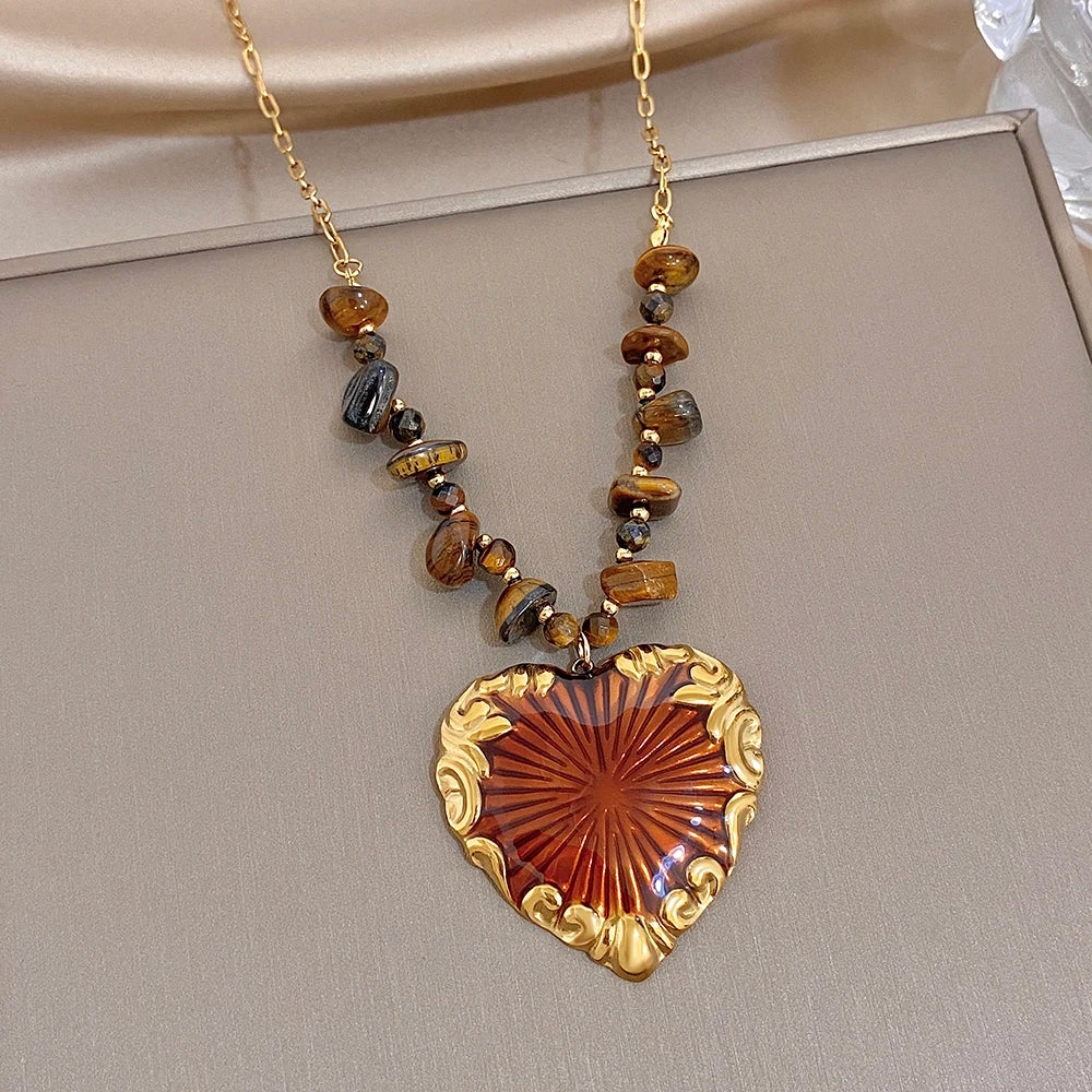 Gold heart pendant necklace with brown and black beads and red sunburst heart charm