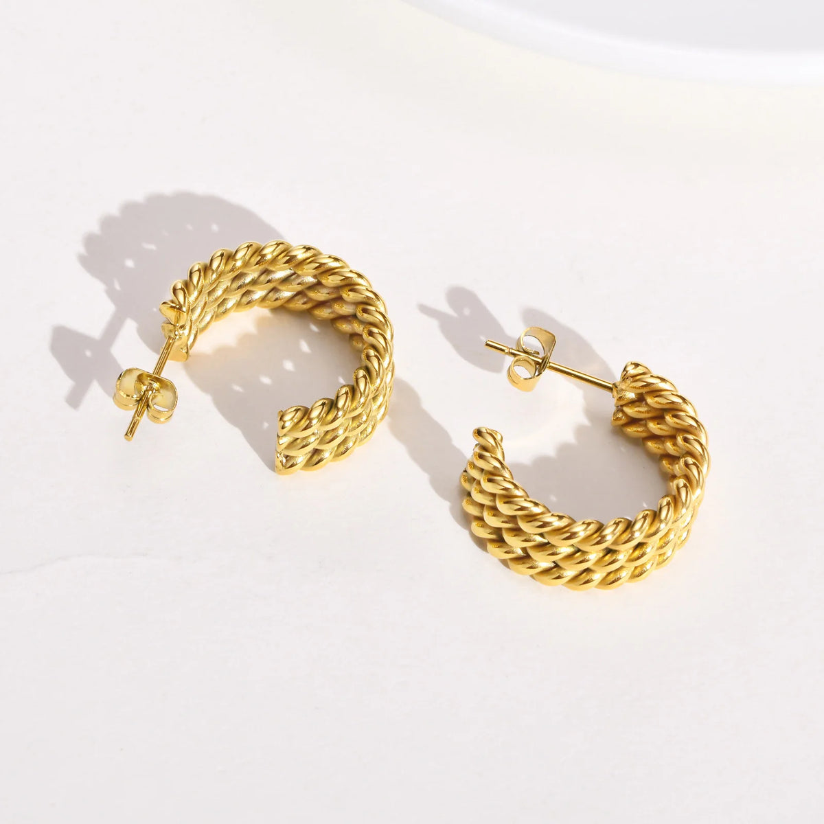 Gold-tone open hoop earrings with twisted rope texture, viewed from above