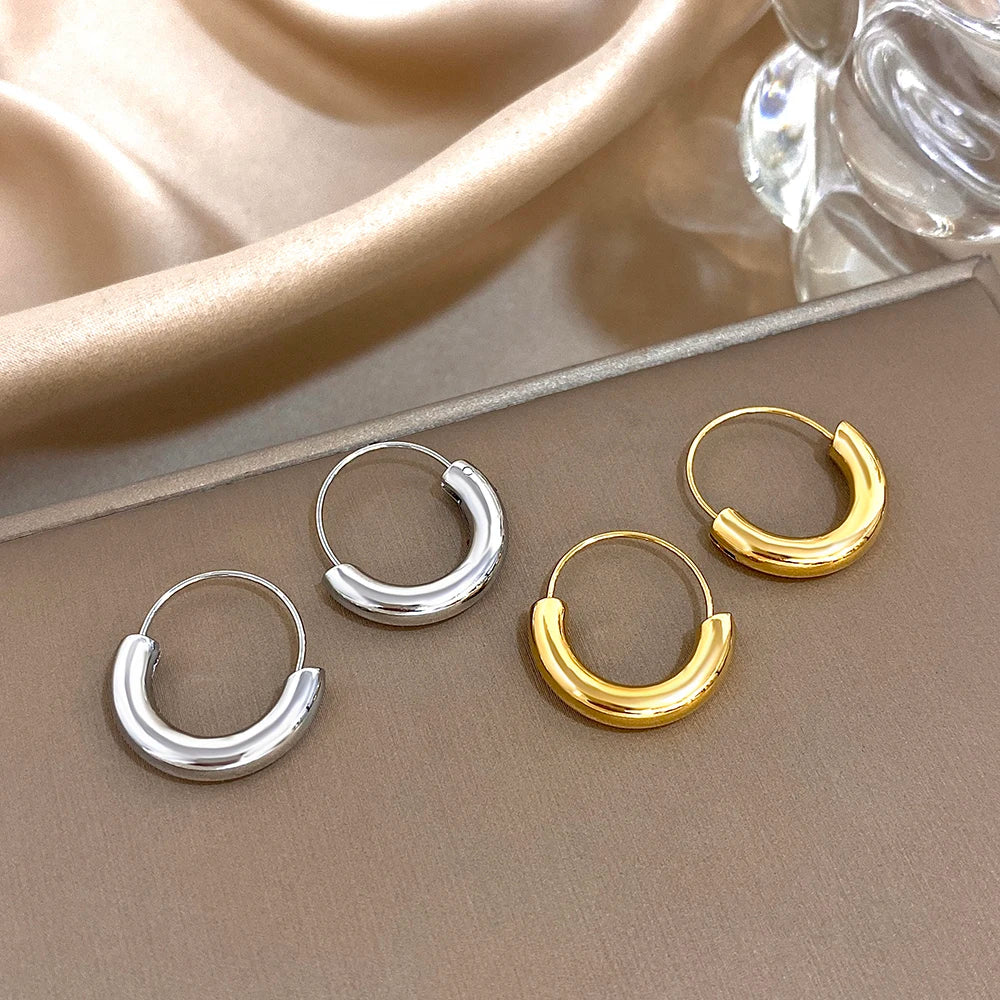 Gold- and silver-tone geometric hoop earrings with glossy, rounded lower halves