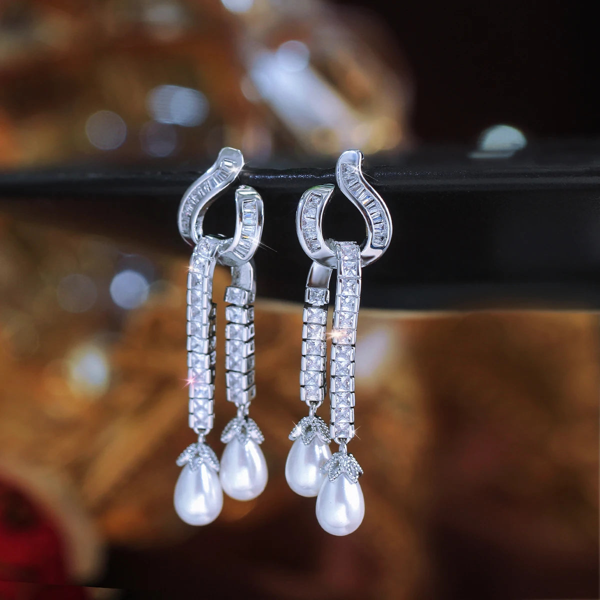 Pair of silver-tone earrings with sparkling zirconia bars and dangling pearl drops.