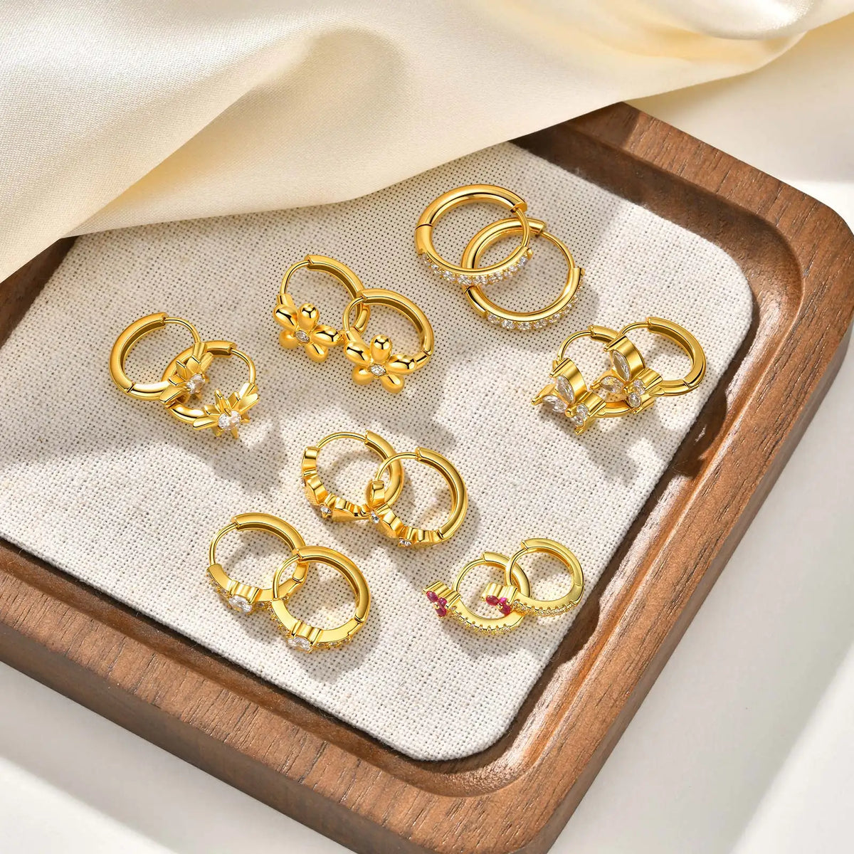 Gold-tone huggie hoop earrings with clear CZ and pink heart-like accents