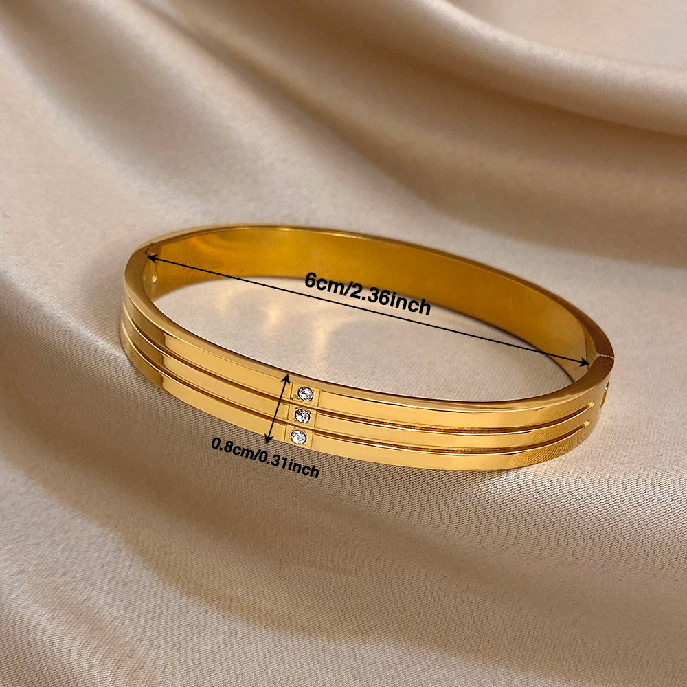 Gold-tone stainless steel wide cuff bangle with crystal row in center