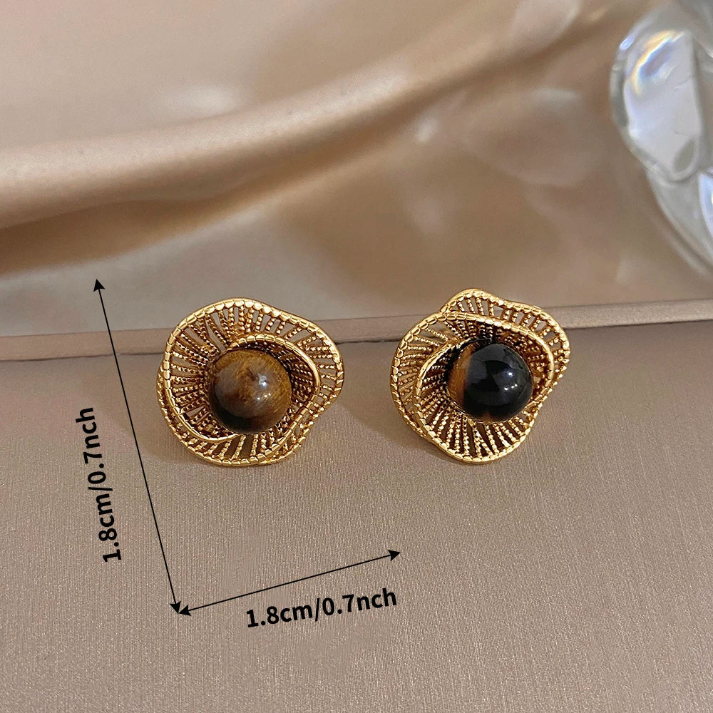 Gold-tone flower stud earrings with dark round stones on flat decorative setting