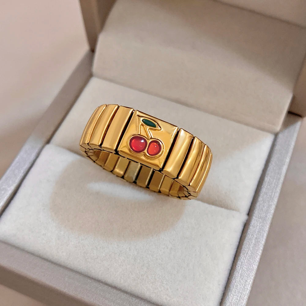 Gold adjustable watchband-style finger ring with red cherry enamel and green leaf accents