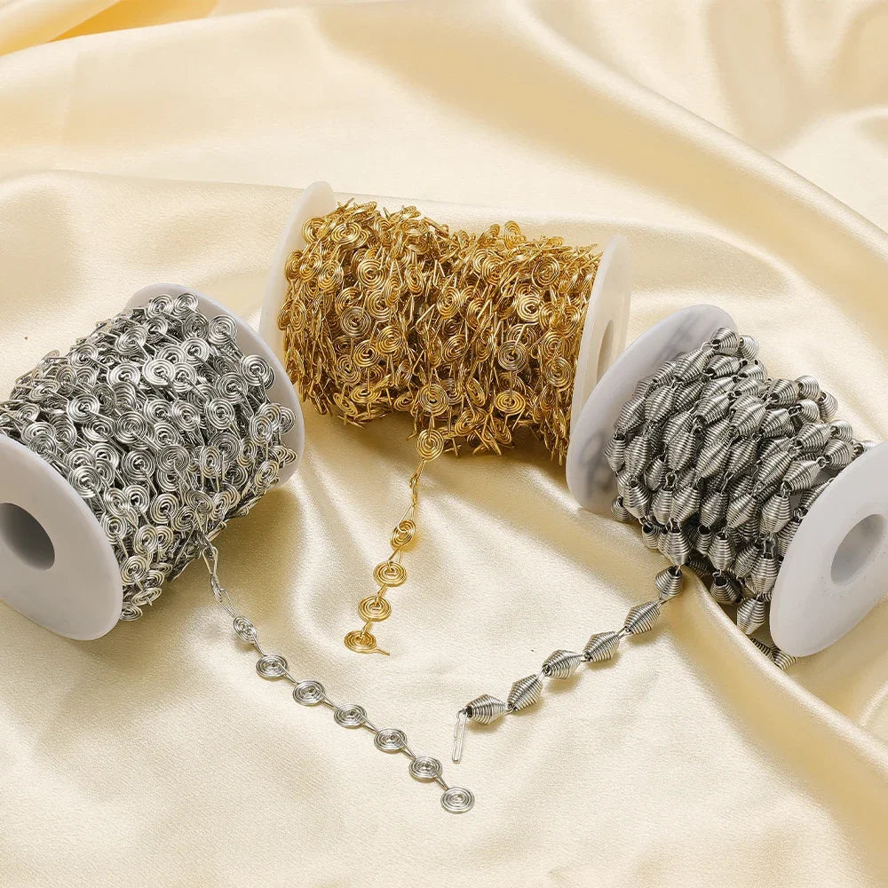 Metal spiral chains on spools in silver, gold, and gray with dangling links