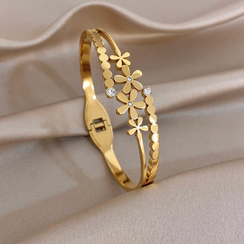 Gold cuff bangle with vertical daisy flower motif and small clear stone accents