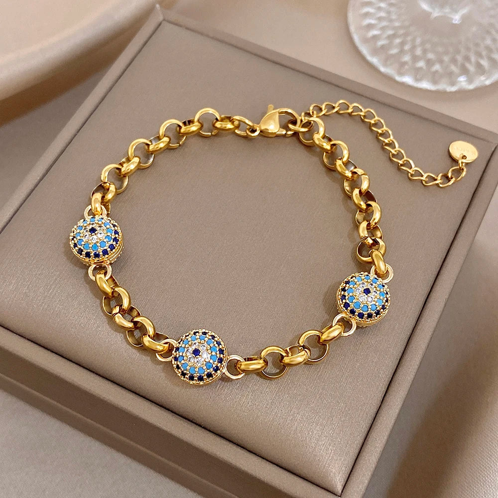 Gold-tone thick chain bracelet with blue evil-eye bead charms and clasp visible