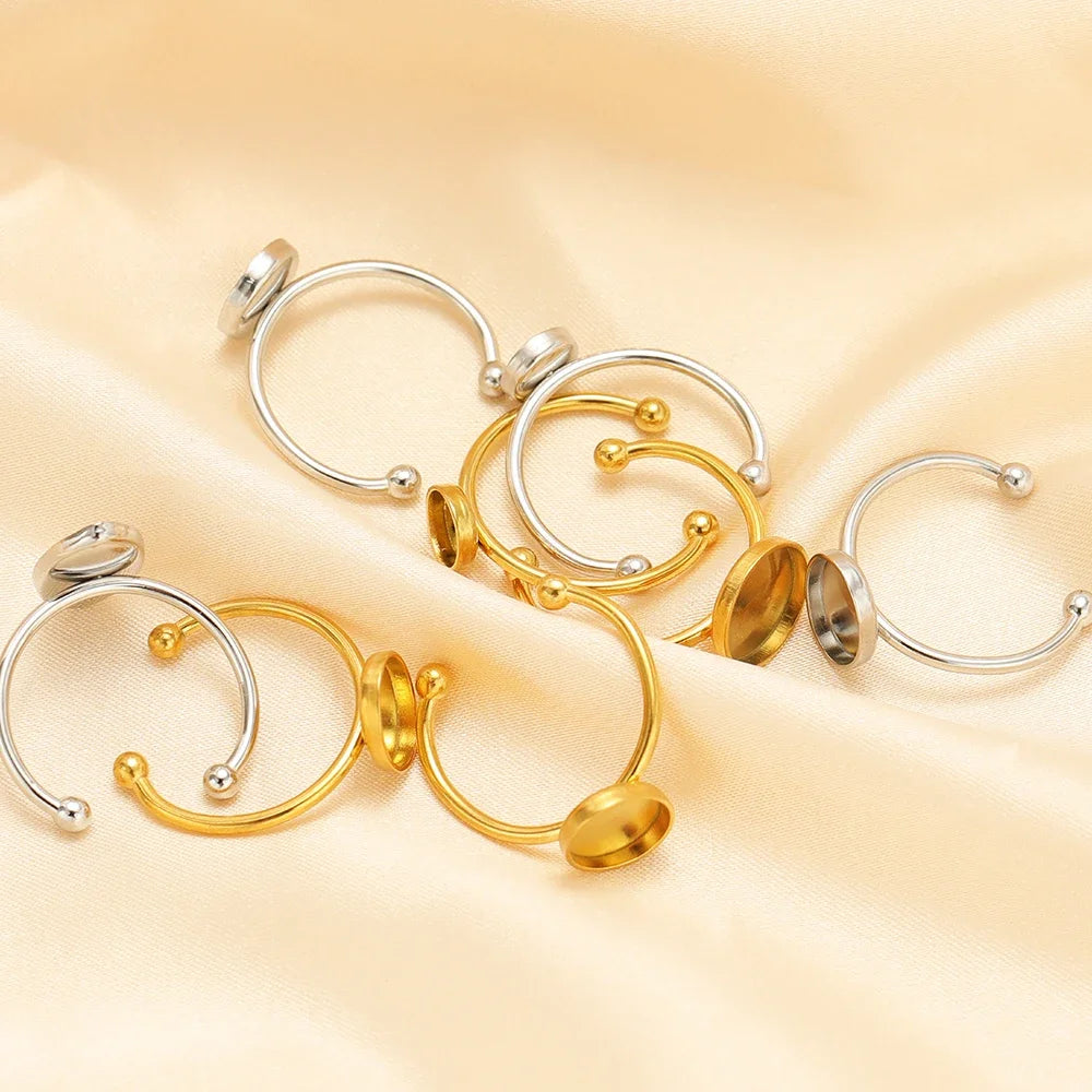 Assorted silver and gold open cabochon ring settings with round blank trays and prongs