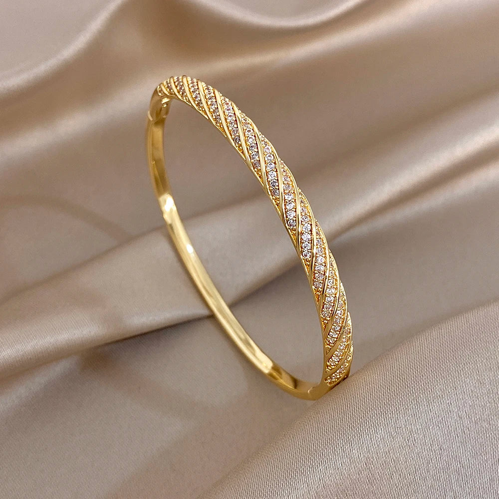 Gold-tone slim twisted crystal inlay bangle, smooth oval profile close-up