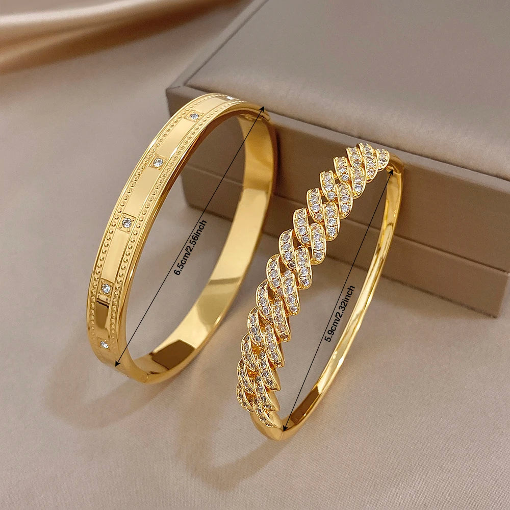 Gold tone hinged bangle pair with clear rhinestone geometric rows and bezel settings.