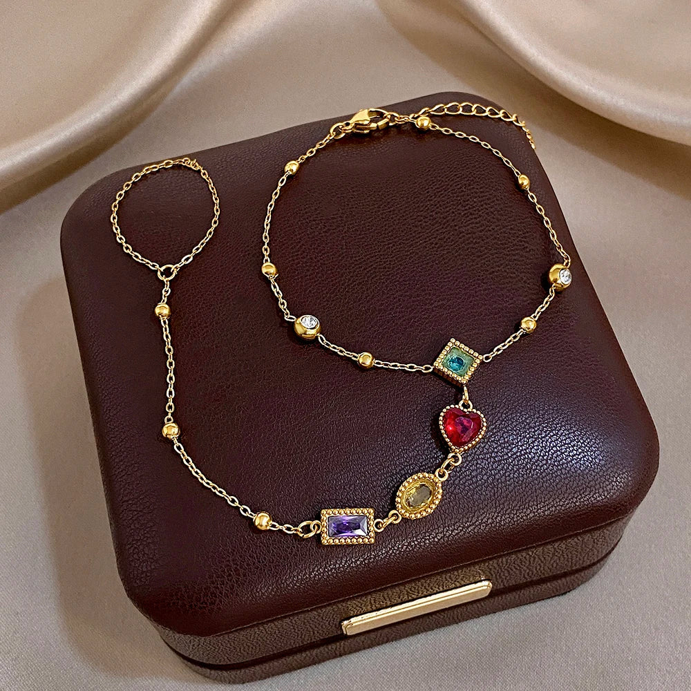 Gold-tone gemstone bracelet with blue, red heart, and purple square dangling charms