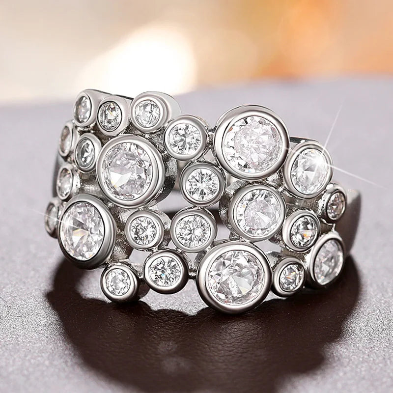 Silver-toned wide ring with large and small round cubic zirconia stones in clusters
