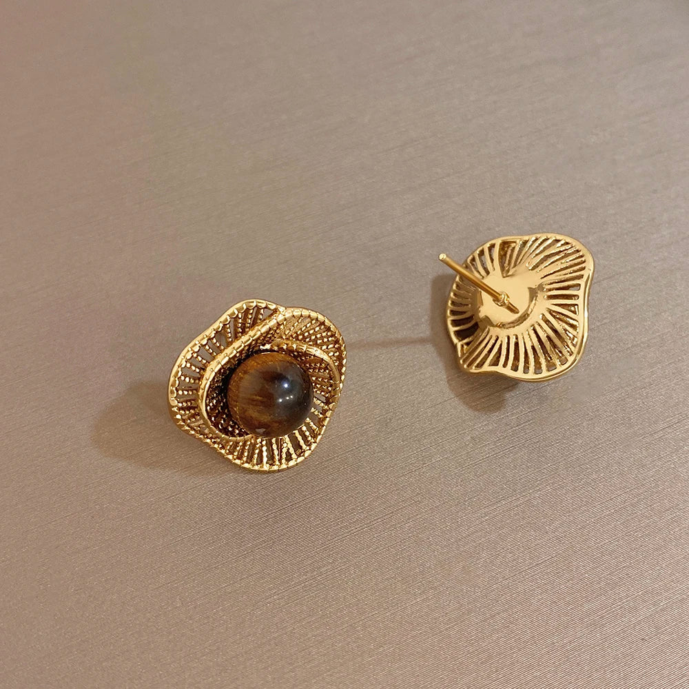 Gold-tone flower stud earrings with dark round bead; gold post backs visible