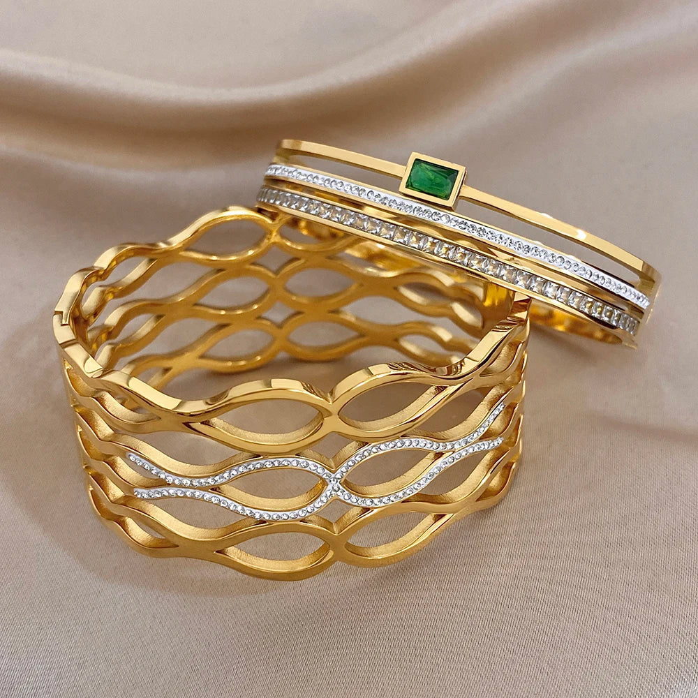 Gold-tone geometric cuff with oval-cut clear stones and green square accent on top bangle