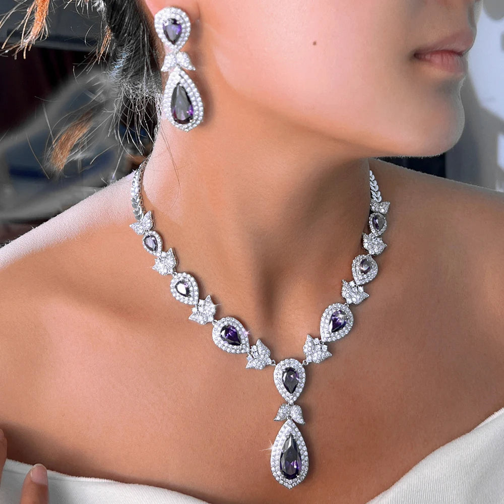 Purple teardrop crystal necklace and drop earrings with clear stone halos and bow accents