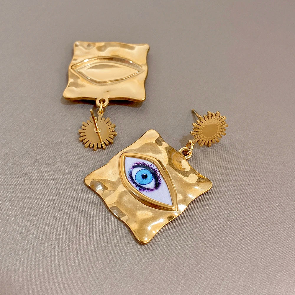 Gold-tone evil-eye drop earrings: hammered squares, blue eye enamel, small sunburst charms