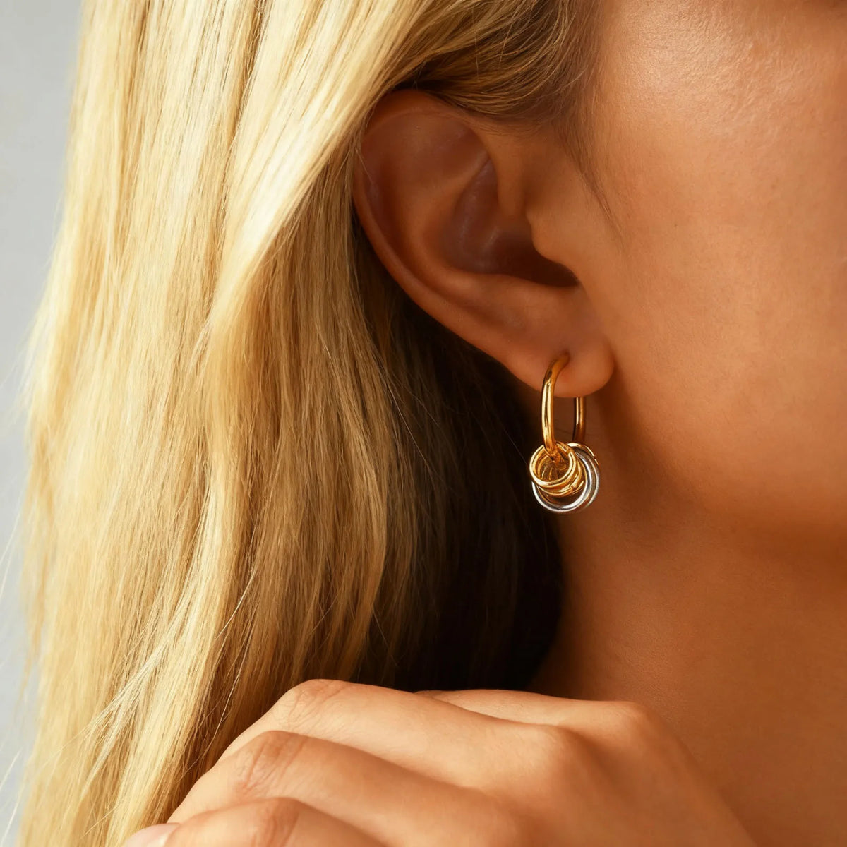 Gold and silver hoop earring with layered rings, worn on an ear.