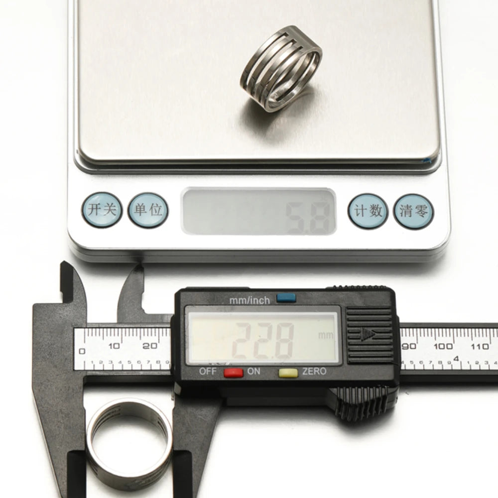 Stainless steel jump ring opener finger ring shown next to digital measurement tools