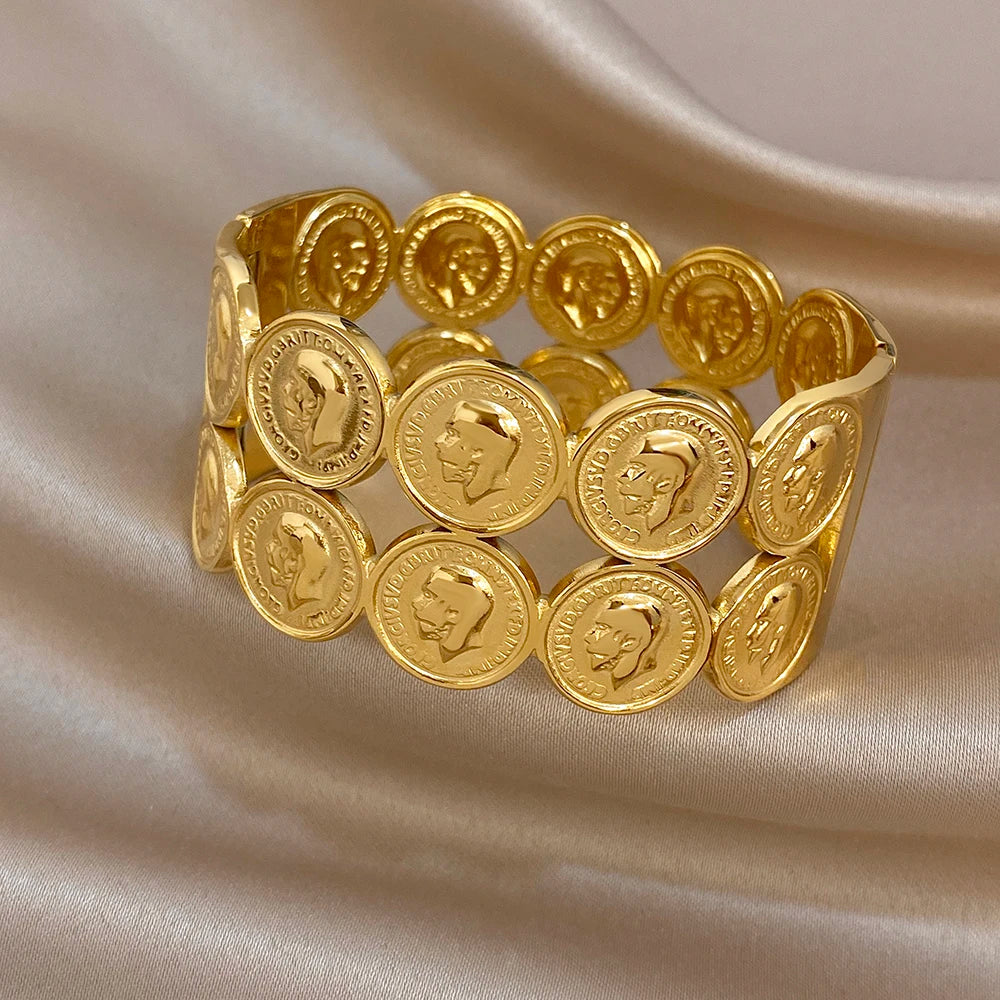Gold plated wide cuff bangle with round coin medallions and human face emblems