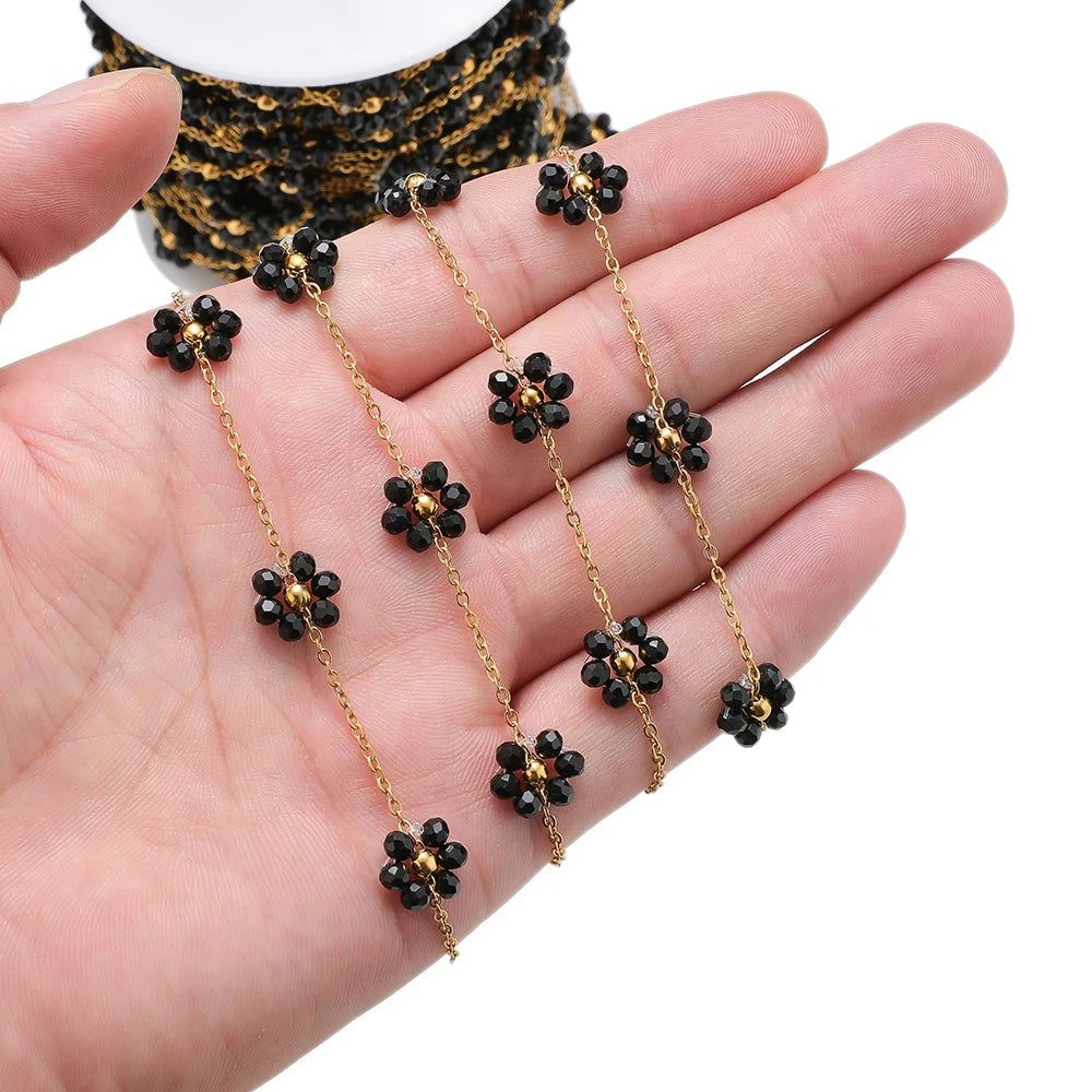 Black daisy flower beaded chain with gold-tone links held in hand